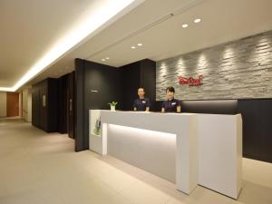 dos hombres parados en un mostrador en un vestíbulo en Red Roof Inn & Suites Osaka Namba Nipponbashi en Osaka