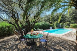 a table and chairs under a tree next to a swimming pool at Les Ilets de L'Eau Blanche in Cavalaire-sur-Mer