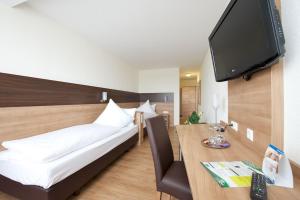 Schlafzimmer mit einem Bett und einem Schreibtisch mit einem TV in der Unterkunft Hotel zur Riss in Biberach an der Riß