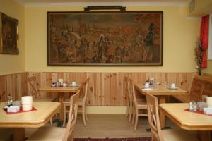 un restaurante con mesas de madera y una pintura en la pared en City Hotel Neunkirchen en Neunkirchen