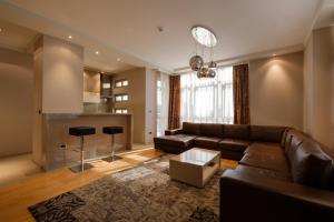 a living room with a brown couch and a kitchen at Apart K Apartments & Rooms in Belgrade