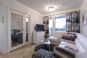 a living room with a white couch and a large window at Tuomas' luxurious suites, Vasko in Rovaniemi