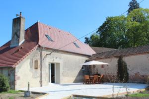 a building with a red roof and a table and chairs at Gîte Domaine St Georges in Bagneux