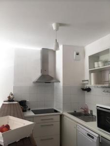 een keuken met een spoelbak en een fornuis bovenste oven bij Charmant appartement - Centre d'Arcachon in Arcachon