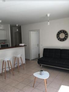 een woonkamer met een zwarte bank en een tafel bij Charmant appartement - Centre d'Arcachon in Arcachon