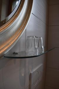 dois copos numa prateleira de vidro debaixo de um espelho em Haus Hilgenfeld em Bad Sooden-Allendorf