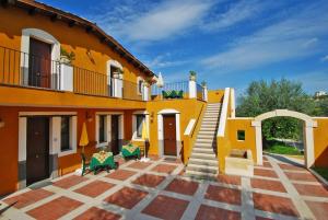 Una gran casa amarilla con escaleras y un patio en Agriturismo Roccadia en Carlentini
