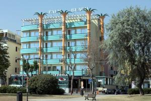 a large building with palm trees in front of it at Hotel Palm Beach B&B SEA VIEW in Rimini