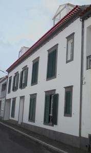 a white building with green windows on a street at Apartamento Silveira in Furnas