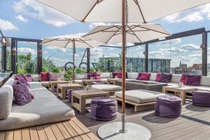 a patio with couches and tables and umbrellas at Hotel Zoo Berlin in Berlin