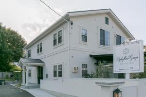 ein weißes Haus mit einem Schild davor in der Unterkunft Guest House Diphylleia Grayi in Hatsukaichi