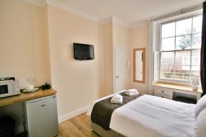 a bedroom with a bed and a tv on the wall at Central Studios Gloucester Place by Roomsbooked in Cheltenham