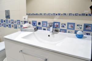 a white sink in a bathroom with pictures on the wall at I Giardini Del Re in Naples +19 photos
