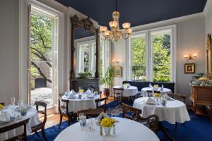 un restaurant avec des tables et des chaises blanches et un lustre dans l'établissement Hamilton Turner Inn, à Savannah