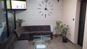 a living room with a couch and a clock on the wall at Complex Friends in Pleven