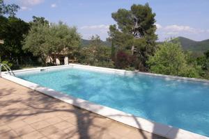 una gran piscina azul con árboles y montañas en el fondo en Gîtes du Mas Icard en Anduze