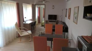 sala de estar con mesa de comedor y sillas de color naranja en Gereben Apartman Pécs, en Pécs