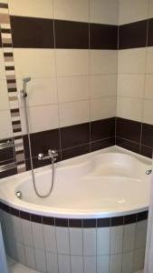 a bath tub in a bathroom with black and white tiles at Gereben Apartman Pécs in Pécs