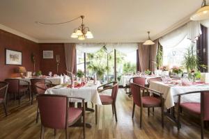 a restaurant with white tables and chairs and windows at Kleines Hotel Wemhoff in Winterberg