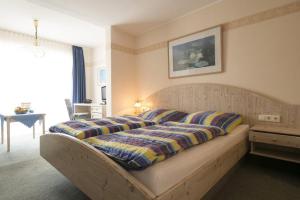 a bedroom with a bed with a striped blanket on it at Kleines Hotel Wemhoff in Winterberg +33 photos