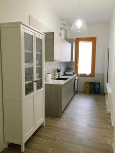uma cozinha com armários brancos e piso em madeira em Ca' Lucia Apartment em Veneza