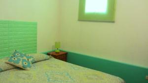 a bedroom with a bed with a green headboard and a window at Hostal Odeón in Valparaíso