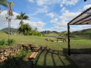 a garden with a bench and a stone wall and palm trees at Arte de Minas in São Gonçalo do Sapucaí