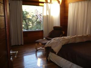 a bedroom with a bed and a chair and a window at Arroyo Escondido in La Cumbrecita