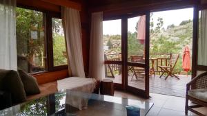 sala de estar con mesa de cristal y balcón en Arroyo Escondido en La Cumbrecita