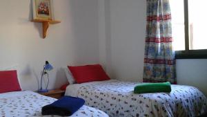 a bedroom with two beds with red and blue sheets at Hostal Casa Amaya in Vallehermoso
