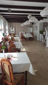 jadalnia z białymi stołami, krzesłami i żyrandolami w obiekcie Restauracja i Noclegi Pod Sikorką w mieście Kobior +8 zdjęć