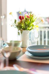 un tavolo con piatti e un vaso pieno di fiori di Apartment11 Wartburg a Colonia