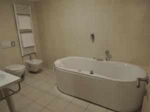 een witte badkamer met een bad en een toilet bij San Giorgio Hotel in San Giórgio di Nogaro