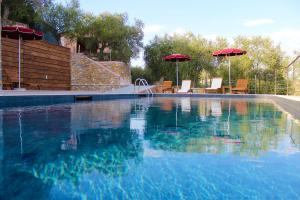 a swimming pool with two umbrellas and chairs and a swimming pool at A Baracca du Pei in Imperia