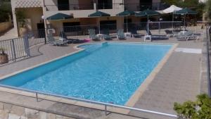 una piscina en un hotel con sillas y sombrillas en Irida Apartments -EX BLAZIS HOUSE, en Almyrida
