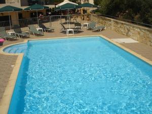 una gran piscina azul con sillas y sombrillas en Irida Apartments -EX BLAZIS HOUSE, en Almyrida