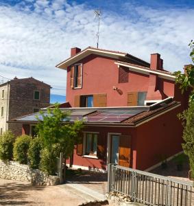 a red house with a fence in front of it at Cris Apartments in SantʼAmbrogio di Valpolicella