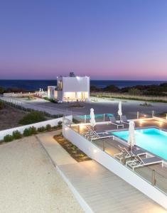 a house with a swimming pool next to the ocean at Aegean Horizon Beachfront Villas in Gennadi