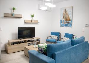 a living room with two blue chairs and a tv at Aegean Horizon Beachfront Villas in Gennadi