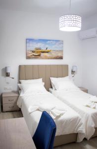 sypialnia z 2 łóżkami i niebieskim krzesłem w obiekcie Aegean Horizon Beachfront Villas w mieście Jenadi