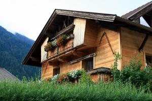 una casa de madera con flores a un lado. en Ferienwohnung Felix, en Neustift im Stubaital