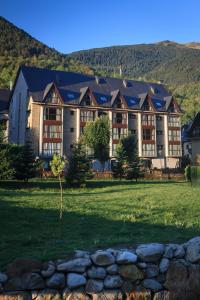 a large building with a grass field in front of it at Aparthotel La Vall Blanca in Vielha