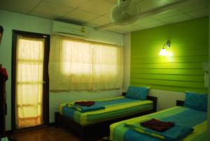 two beds in a room with green walls at Sweet Home Patong in Patong Beach