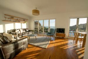 a living room with a leather couch and a television at The Black Pearl, Waiheke Island in Oneroa