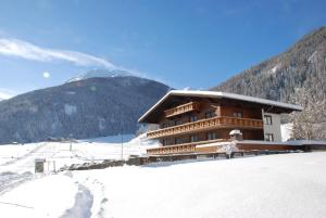 ein großes Holzgebäude im Schnee mit einem Berg in der Unterkunft Ferienhaus Tirolerhof in Kals am Großglockner