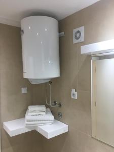 La salle de bains est pourvue d'une armoire blanche et de serviettes sur une étagère. dans l'établissement Apartment Posejdon, à Belgrade 25 autres photos