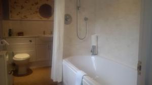 a bathroom with a bath tub and a toilet at Grayling House in Stoford