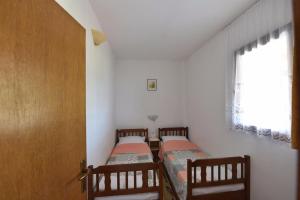 two twin beds in a room with a window at Apartmani Marko in Gdinj