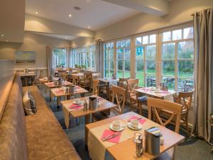 a restaurant with tables and chairs and windows at Hotel Spiekeroog in Spiekeroog