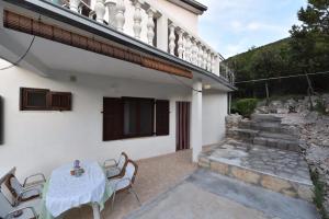a white house with a table and chairs on a patio at Apartmani Marko in Gdinj